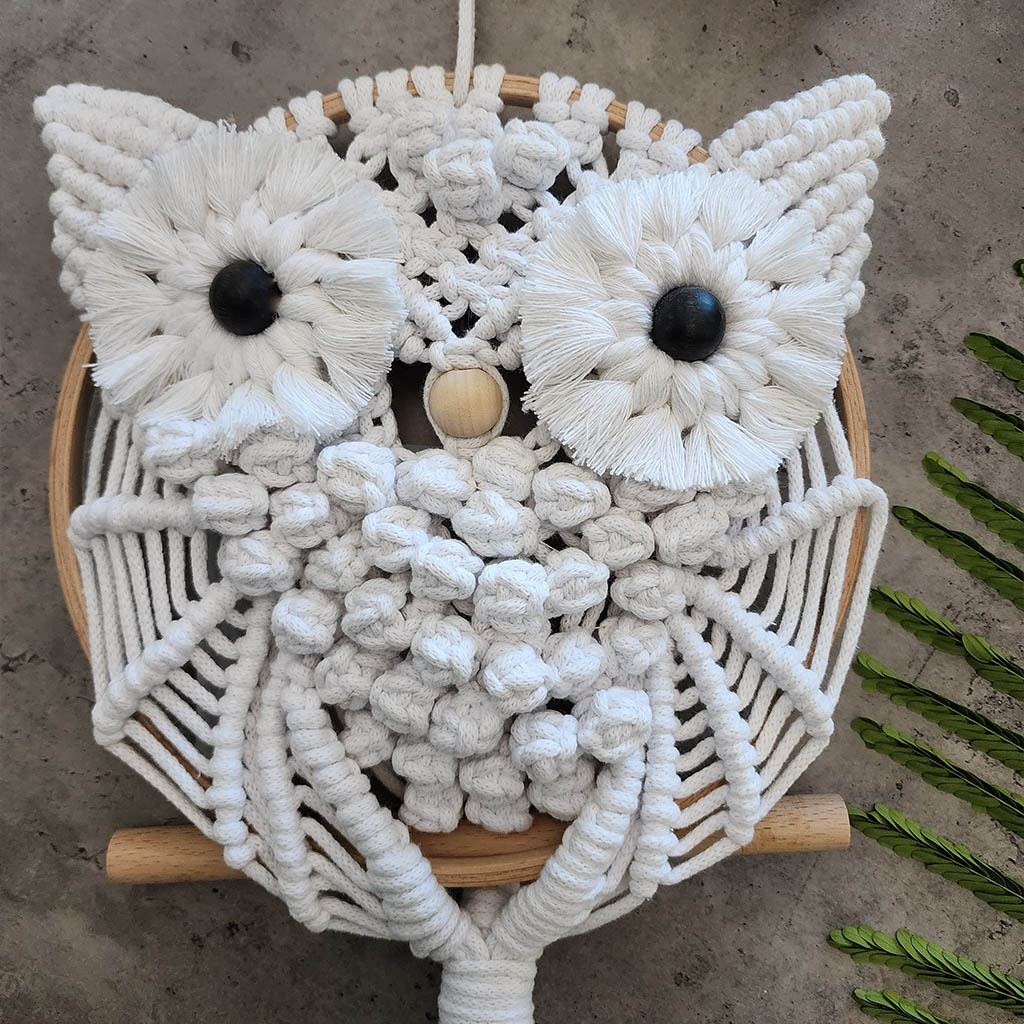 “Wise Guardian” by ArtixHub – natural-tone macramé owl perched on a wooden dowel, featuring textured bobbles and fringe that evoke nocturnal wisdom. Ideal for home offices, libraries, or bohemian living rooms, adding a touch of woodland magic to UAE décor.