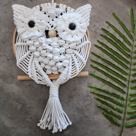 “Wise Guardian” by ArtixHub – natural-tone macramé owl perched on a wooden dowel, featuring textured bobbles and fringe that evoke nocturnal wisdom. Ideal for home offices, libraries, or bohemian living rooms, adding a touch of woodland magic to UAE décor.